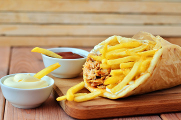Gyro on a wooden table. Gyro, fries and two sauces on wooden background