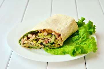 Healthy homemade shawarma on a white plate with lettuce leaves on a white wooden table. Healthy food