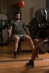 Fototapeta na wymiar Young Bodybuilder Exercising Triceps On Machine