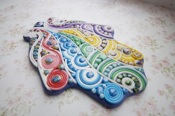 hand-molding khamsa from polymer clay  on a wooden base