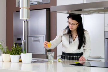 Squeezing lemon juice by woman in modern kitchen