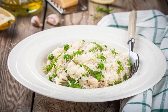 Homemade risotto with chicken, green peas, arugula and parmesan