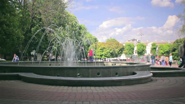 Time lapse park with fountains. People resting in the park and photographed with water.
