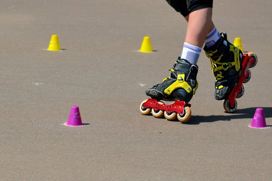 Leggs of roller skating young girl training with inline rollerblades.