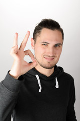 Everything is OK! Happy young man in shirt and tie gesturing OK sign and smiling while standing against grey background