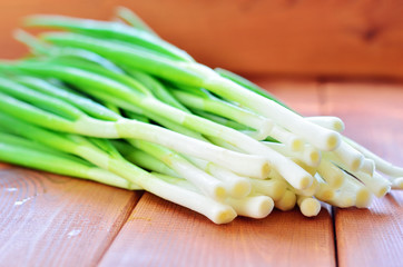  Green onions on a wooden background. Side view