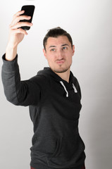 Closeup of young handsome man looking at smartphone and taking selfie