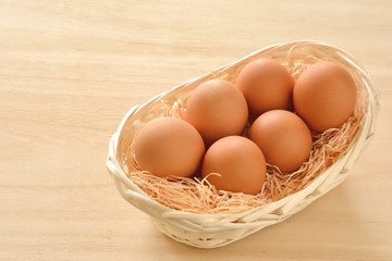 籠に入った赤玉の卵　木目背景

