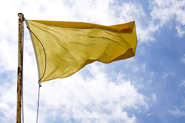 Yellow flag waving on the blue sky.