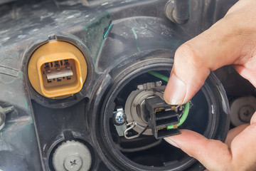 Mechanic changing car headlight in a workshop