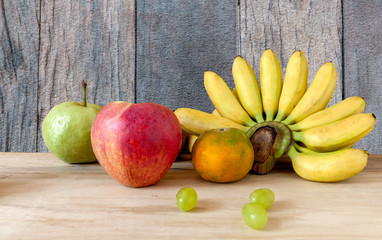 Fresh fruit apple grapes banana and orange with wood background