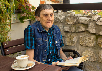 A man with cerebral palsy reading a book. - 110002430