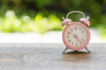 the pink analog alarm clock with the garden background