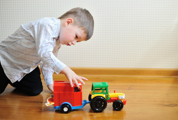 child boy toddler playing with toy car indoors