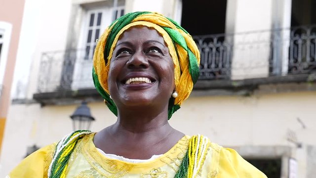 Brazilian woman of African descent, smiling, dressed in traditional Baiana attire in Pelourinho, Salvador, Bahia, Brazil