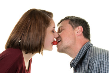 Happy couple kissing with a strawberry in their mouth
