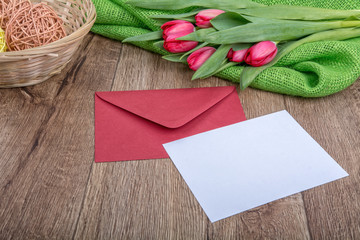 Envelope with sheet of paper and tulips on a wooden background