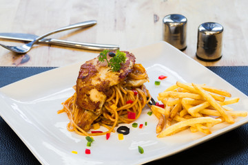chicken steak on spaghetti with tomato sauce and french fries in