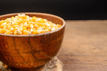 Dried corn seed in wooden bowl on wooden table