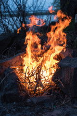 Bonfire between rocks in the wood with lake on the background
