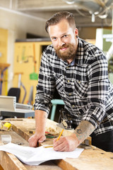 Smiling carpenter planning work in the workshop