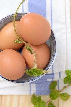 brown eggs in a bowl with mint leaf on a napkin closeup