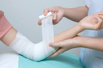 Nurse applying bandage to patient injured elbow