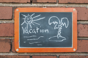 Tafel an einer Ziegelwand mit Text / Tafel an einer Ziegelwand mit Text Vacation.