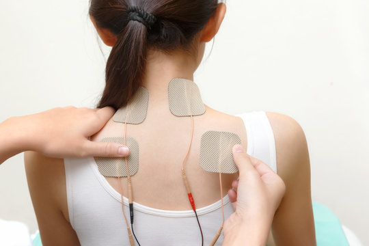Closeup of therapist placing electrodes on woman's back