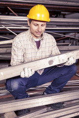 young metalworker controls some metal bars in steel mill