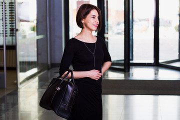  Happy businesswoman in black dress walking with briefcase in sh