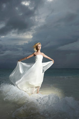 Fototapeta na wymiar Gorgeous bride standing and posing under threatening clouds at s