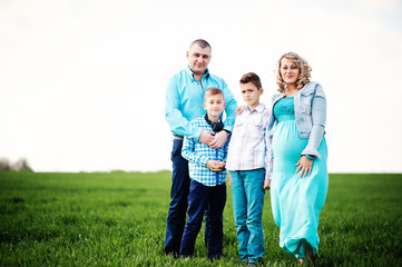 Happy pregnant family with two sons, dressed in a turquoise clot