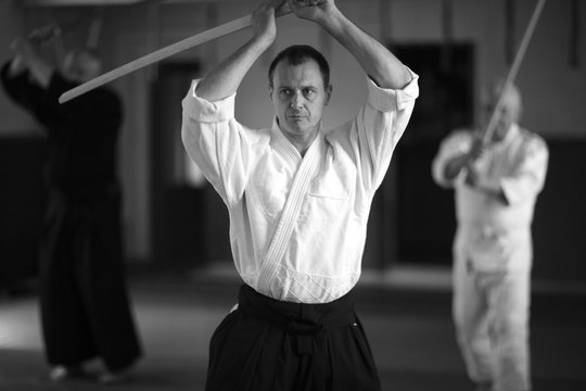 Aikidoka daily training with sword; portrait of a middle aged man with raised hands holding bokken