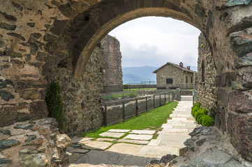 Fototapeta na wymiar Stone arch in the courtyard of Sacra di San Michele - Saint Michael Abbey, ancient religious complex on Mount Pirchiriano in St Ambrogio, Piedmont, Italy.