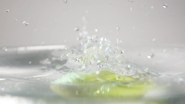 Tasty Green apple plunging into clean transparent water with stunning liquid spray on white background in slow motion. Sony rx 10 ii horisontal shooting