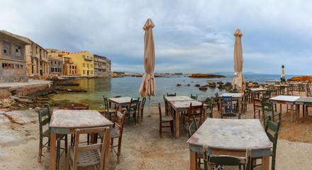 Empty outdoor cafe on the seashore in the cloudy morning, Chania, Crete, Greece