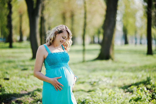 Portrait of happy pregnant woman dressed in a turquoise dress at