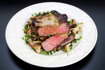 Tasty Beef Mignon steak with mushrooms and herbs on plate.
