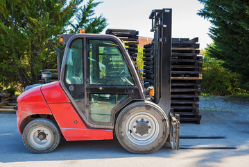 Forklift standing outdoors against the backdrop of wooden pallets