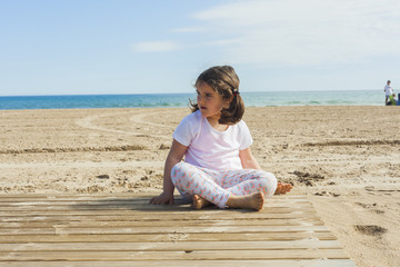 Girl playing with the sand in the beach in a sunny day in spring