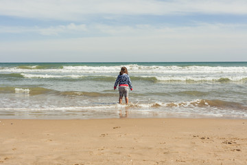 Rear view full shot girl walking to the shore of the beach in a