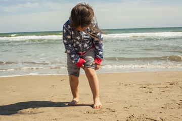 Fototapeta na wymiar Full shot girl in the shore of the beach in a sunny day in sprin