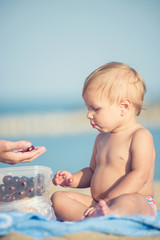 Baby playing with toys on the sandy beach near the sea. Cute little kid in  sand on tropical beach. Ocean coast.
