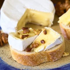 Baguette mit Camembert Käse und Walnuss, fotografiert mit natürlichem Licht (Selektiver Fokus, Fokus auf die vorderen Walnuss Stücke auf dem Brot)