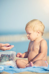 Baby playing with toys on the sandy beach near the sea. Cute little kid in  sand on tropical beach. Ocean coast.