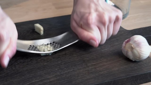 chef crushes garlic cloves on a cutting board