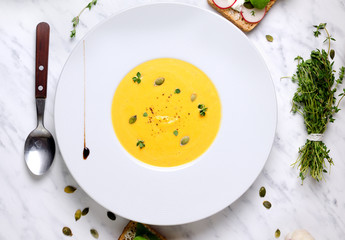 Pumpkin soup in a bowl with spoon on a marble