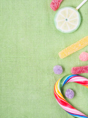Fruit lollipops and candies on green textured napkin, copy space. Vertical image