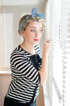 Closeup picture of beautiful blond pinup girl looking through windows